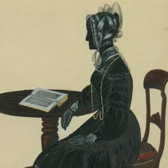 Painted and gilded silhouette of a lady seated at a table with an open book