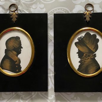 A pair of silhouettes painted on plaster with gilding