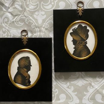 A pair of silhouettes painted on plaster with gilding